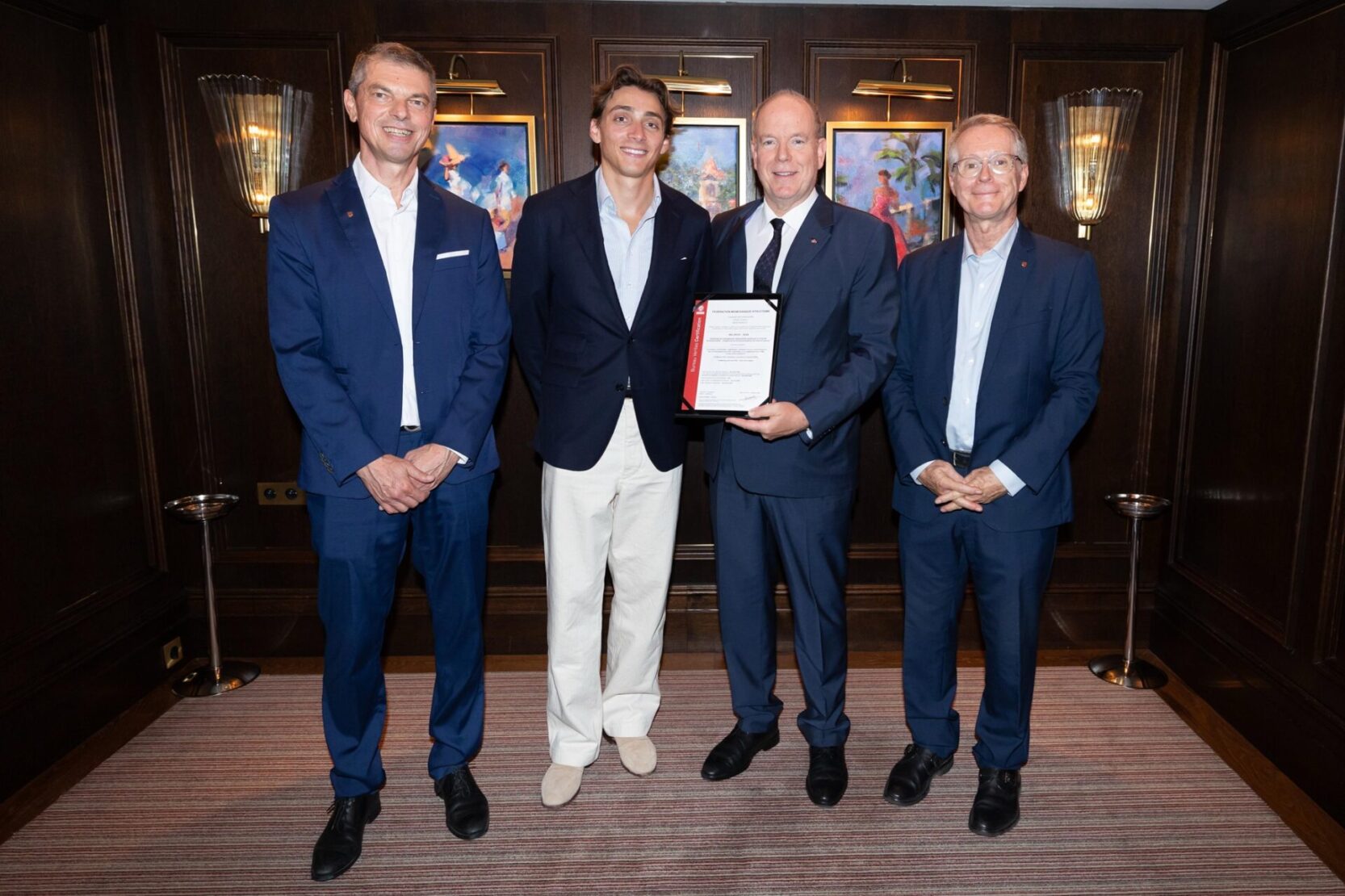 Le Prince Albert II tenant la certification ISO 20121:2024 délivrée à la Fédération monégasque d'athlétisme, au côté de Frédéric Coquard, Mondo Duplantis et Rodolphe Berlin.